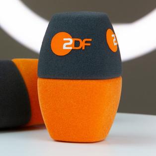 Zwei Mikrofon-Windschützer des ZDF auf einem Tisch.