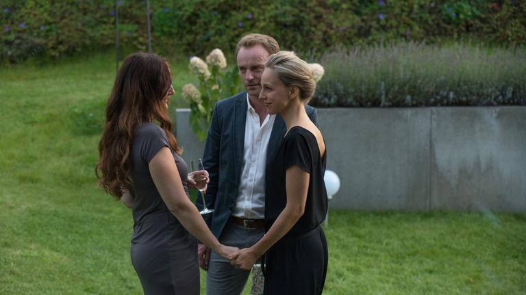 "Ein Mann unter Verdacht": Anja (Deborah Kaufmann), Thomas (Mark Waschke) und Lavinia (Petra Schmidt-Schaller) führen ein vertrauliches Gespräch. Sie stehen im Garten.