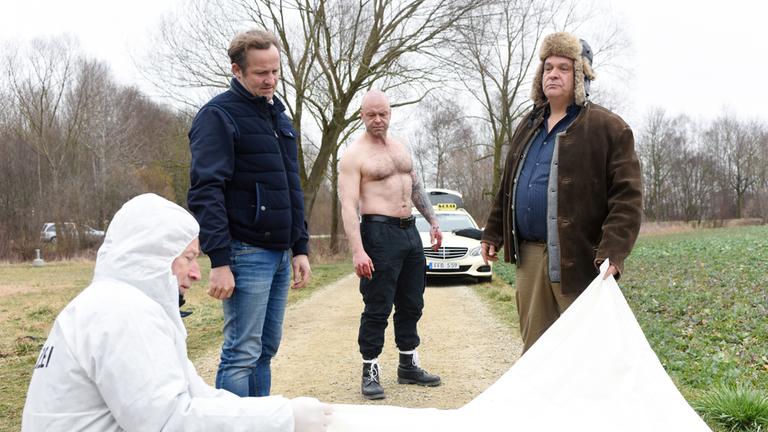 Schwarzach 23 – und die Jagd nach dem Mordsfinger": Fassungslos blicken Kommissar Germinger (Maximilian Brückner), der Polizeichef (Titus Horst) und der Taxifahrer (Robert Gallinowski) auf die Leiche im Feldweg.