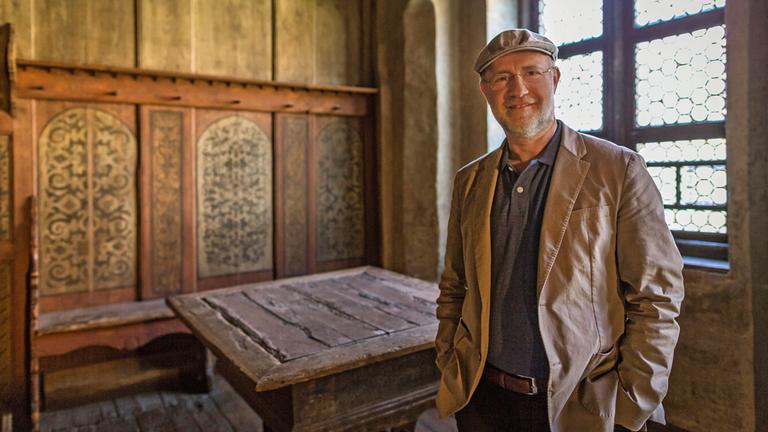 "Der große Anfang - 500 Jahre Reformation": Harald Lesch steht in der Lutherstube im Lutherhaus und blickt lächelnd in die Kamera.