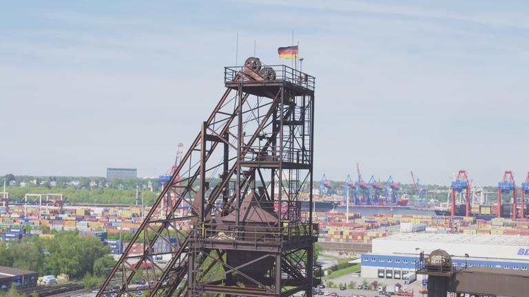 "Neues Wirtschaftswunder - Wer gewinnt beim Aufschwung?": Blick auf einen Förderturm, auf dem eine Deutschlandfahne gehisst ist.