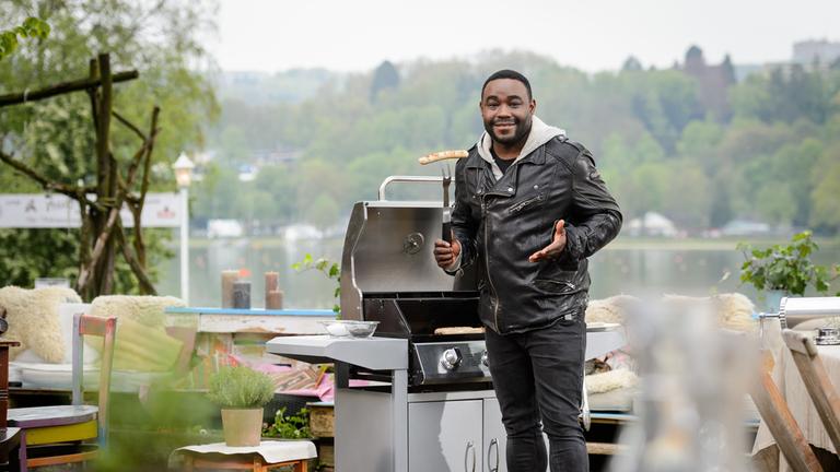"ZDFzeit - Bratmaxe, Bruzzler & Co.": Nelson Müller steht mit einer Bratwurst am Grill.