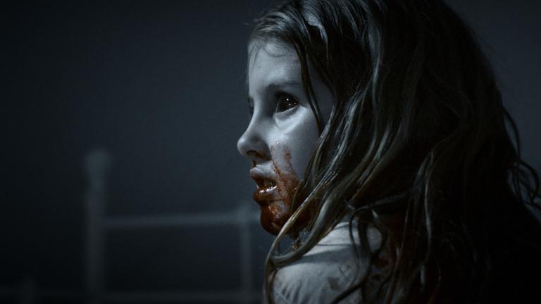 "What We Become":  Maj (Ella Solgaard) ist in einer Nahaufnahme zu sehen. Ihre Augen sind dunkel und ihre Mund ist blutverschmiert.