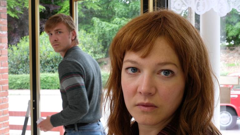 "Verräter - Tod am Meer": Großaufnahme von Nina (Hannah Herzsprung) und Martin (Albrecht Schuch) im Hintergrund. Beide blicken in die Kamera.