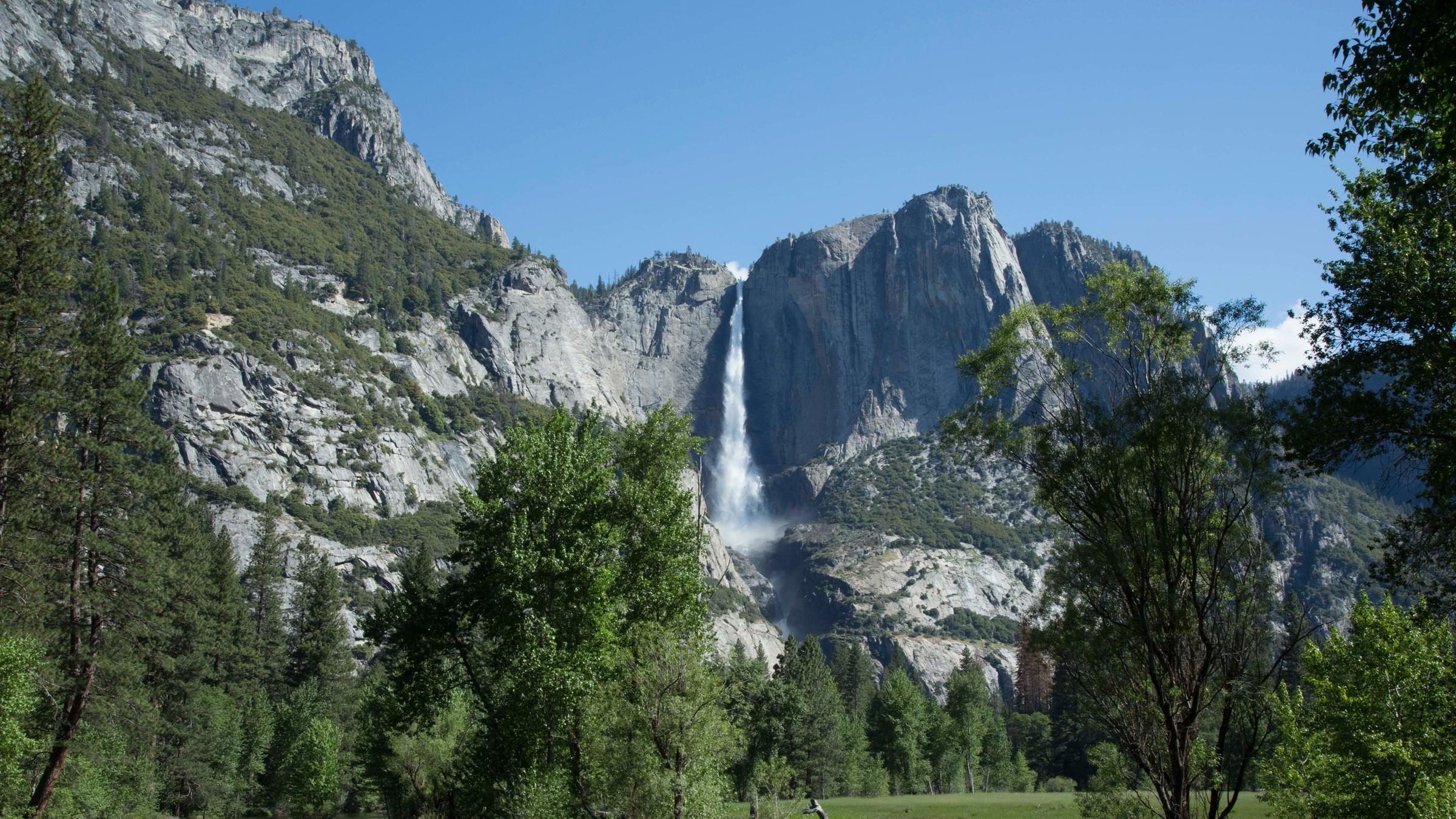 "Im Zauber der Wildnis - Ein kalifornischer Traum: Der Yosemite Nationalpark": Blick in den Yosemite Nationalpark mit Bergen, Wasserfall und Bäumen.