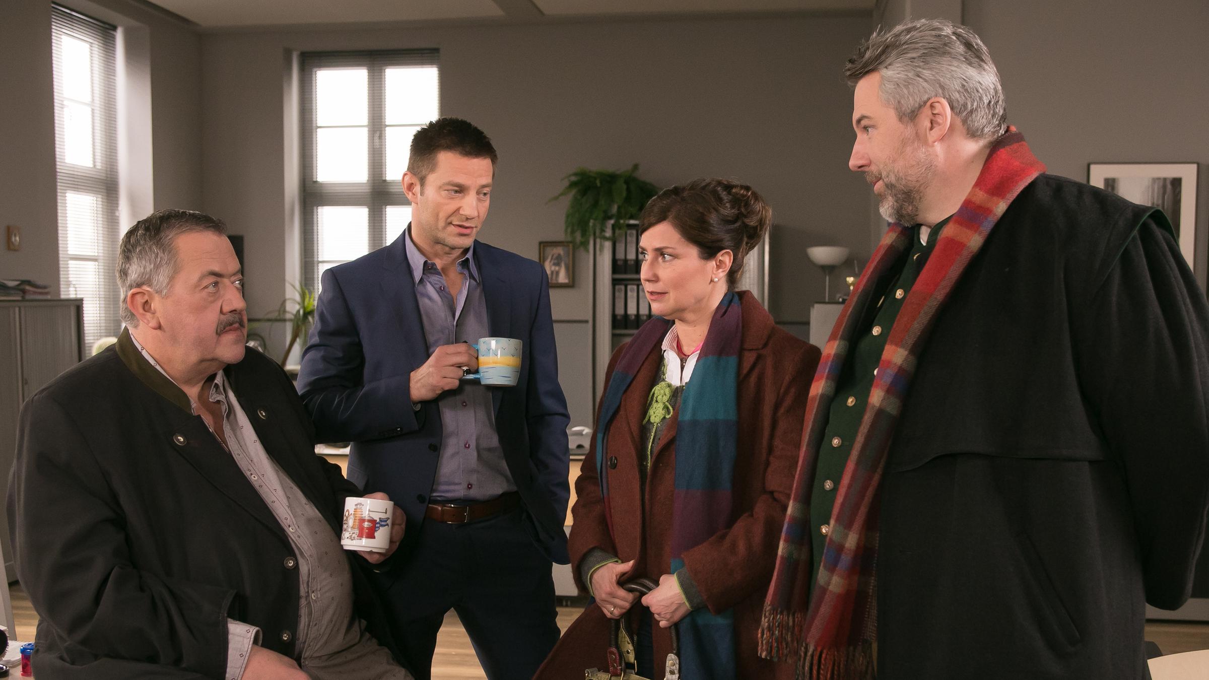 "Die Rosenheim-Cops - Der Schein trügt": Die Kommissare Hofer (Joseph Hannesschläger) und Hansen (Igor Jeftic) stehen mit Hilde Stadler (Isabel Mergl) und Kommissar Stadler (Dieter Fischer) im Kommissariat. Die drei Männer schauen auf Hilde Stadler, die ihnen etwas erzählt.