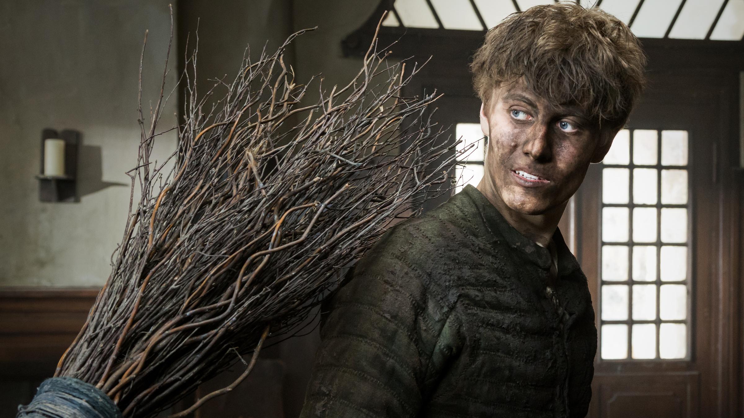 "Der Zauberlehrling": Im Inneren der Apotheke steht Valentin (Max Schimmelpfennig) mit von Dreck schwarzem Gesicht und gekleidet in einen wattierten, dunkelgrünen Wams. Mit großen Augen dreht er sich einem Reisigbesen zu, der Valentin auf die Schulter schlägt.