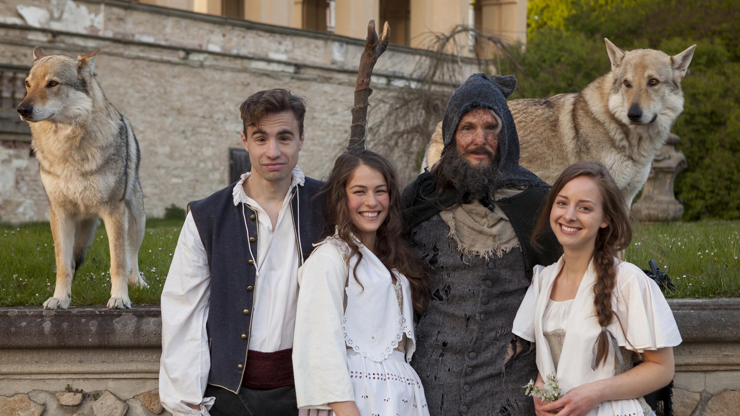  "Rübezahls Schatz": Vor dem Hintergrund der Mauern eines Schlossgartens stehen – mit Blick zum Betrachter – vier Schauspieler. Wir sehen, von links nach rechts: den in Hose mit breitem Hosenbund, weitem Hemd und 