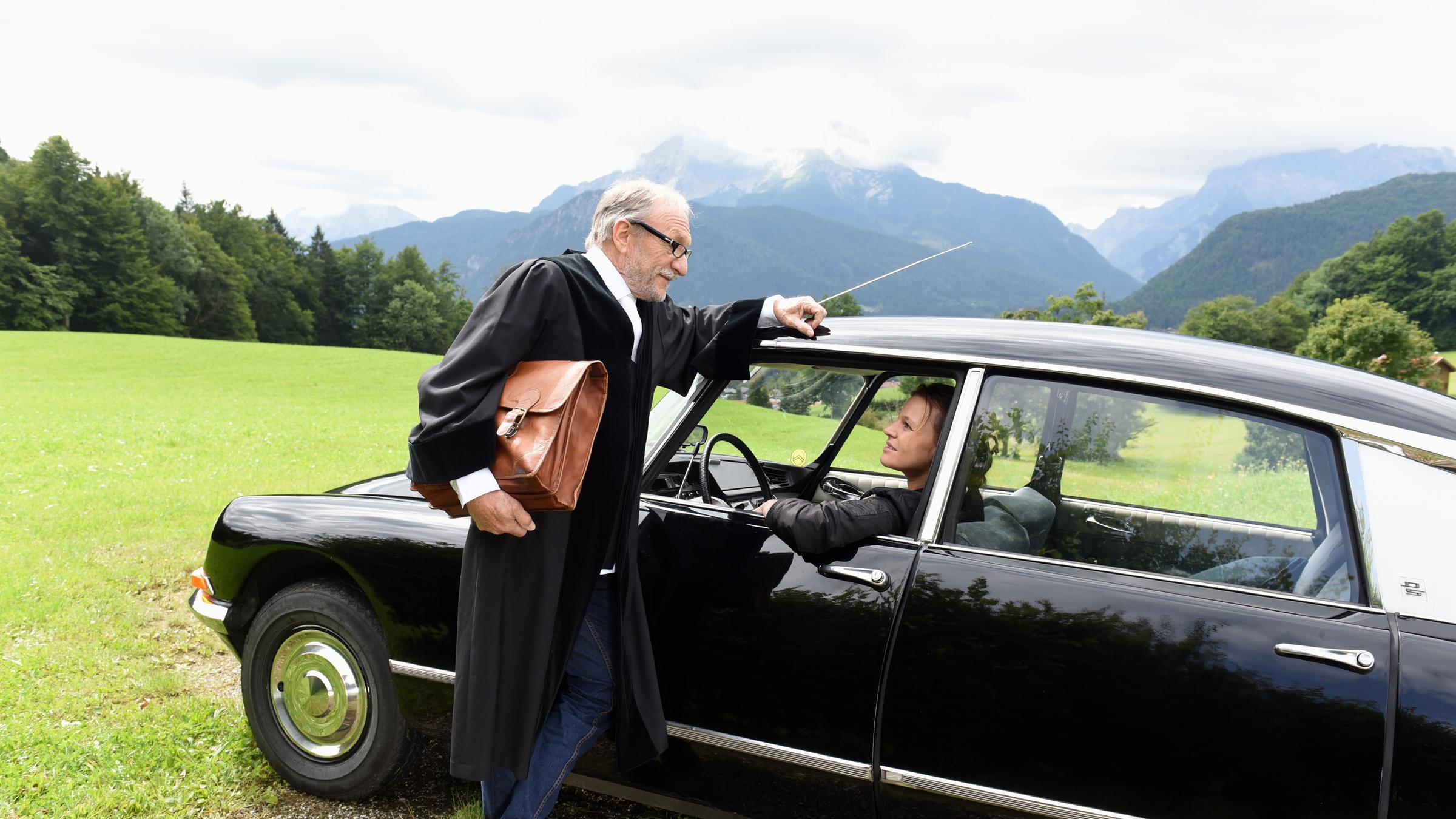 "Über Land - Die Fahrerin": Max Althammer (Franz Xaver Kroetz) lehnt an Frieda Mirkos (Maria Simon) Auto und unterhält sich mit ihr.