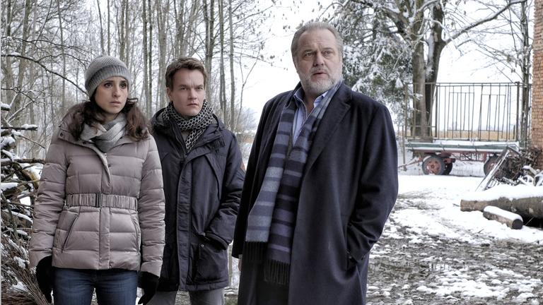 “Der Alte – Kein Entrinnen“: Hauptkommissar Richard Voss (Jan-Gregor Kremp) und seine Ermittler Annabell Lorenz (Stephanie Stumph) und Tom Kupfer (Ludwig Blochberger) befinden sich auf einem verschneiten Hof. Sie blicken alle in dieselbe Richtung.