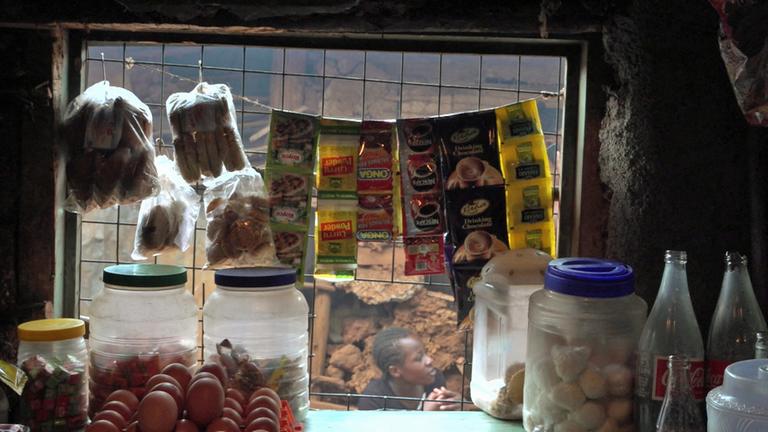 "planet e.: Globale Dickmacher - Wie die Lebensmittelindustrie die Armen verführt": In einem kenianischen Kiosk hängen im Schaufenster industriell verarbeitete Lebensmittel.