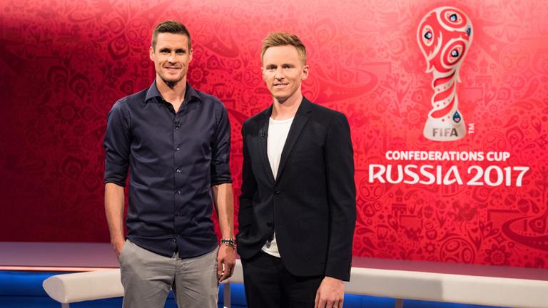 "FIFA Confederations Cup": Sebastian Kehl und Jochen Breyer stehen nebeneinander im Studio. Im Hintergrund ist das Logo des Confederations Cup eingeblendet.