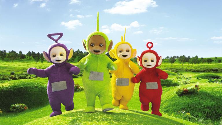 " Teletubbies - Die Gießkanne": Die Teletubbies rennen glücklich und neugierig dreinschauend nebeneinander auf einer grünen, hügeligen Blumenwiese.