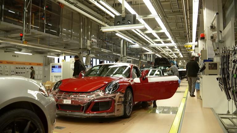 "Die Porsche-Story": Mehrere neue Porsche werden in der Produktionshalle gefertigt.