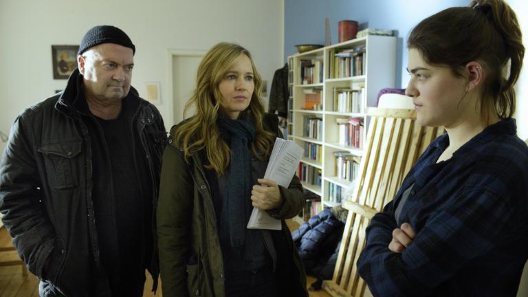  "Ein starkes Team - Tod einer Studentin": Otto Garber (Florian Martens), Linett Wachow (Stefanie Stappenbeck) und Claudia Viereg (Johanna Polley) stehen in Katjas Zimmer beisammen. Linett hält Papiere im Arm und schaut, ebenso wie Otto, zu Claudia, die mit verschränkten Armen vor ihnen steht.