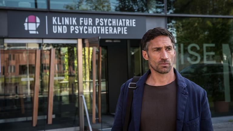 "Der Gutachter - Ein Mord zu viel": Dr. Robert Siedler (Benjamin Sadler) steht vor dem Eingang der Klinik für Psychiatrie und Psychotherapie. Das Schild ist im Hintergrund deutlich zu erkennen.