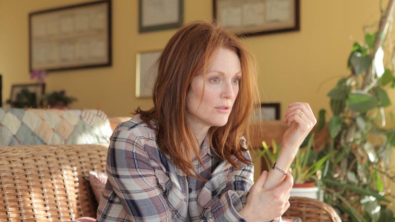 "Still Alice - Mein Leben ohne Gestern": Alice (Julianne Moore) sitzt in einem Korbsessel. Mit der rechten Hand greift sie an ihren linken Arm. Ihr Gesichtsausdruck ist verwirrt.