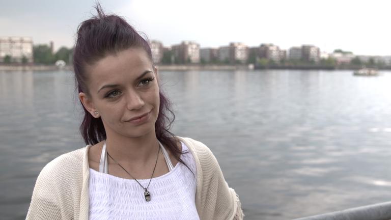 "Bordell Deutschland": Nahaufnahme von Cleo. Im Hintergrund sind Wasser und Gebäudekomplexe zu sehen.