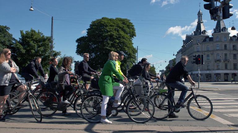 "Unterwegs auf zwei Rädern": Barbara Hahlweg wartet mit anderen Radfahrern an einer Kreuzung.