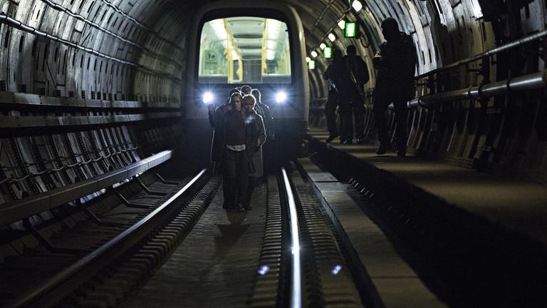 "Countdown Copenhagen - Tag 2": Bewaffnete Männer bewachen eine Gruppe von Menschen, die zu Fuß in einem U-Bahn-Tunnel laufen.