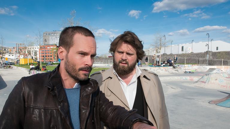 "Ein Fall für zwei - Ohne Skrupel": Benni (Antoine Monot, Jr.) und Leo (Wanja Mues) stehen inmitten eines großen Skateparks. Leo deutet mit seiner Hand auf etwas, das sich in der Ferne befindet. Benni sieht ihn fragend an.