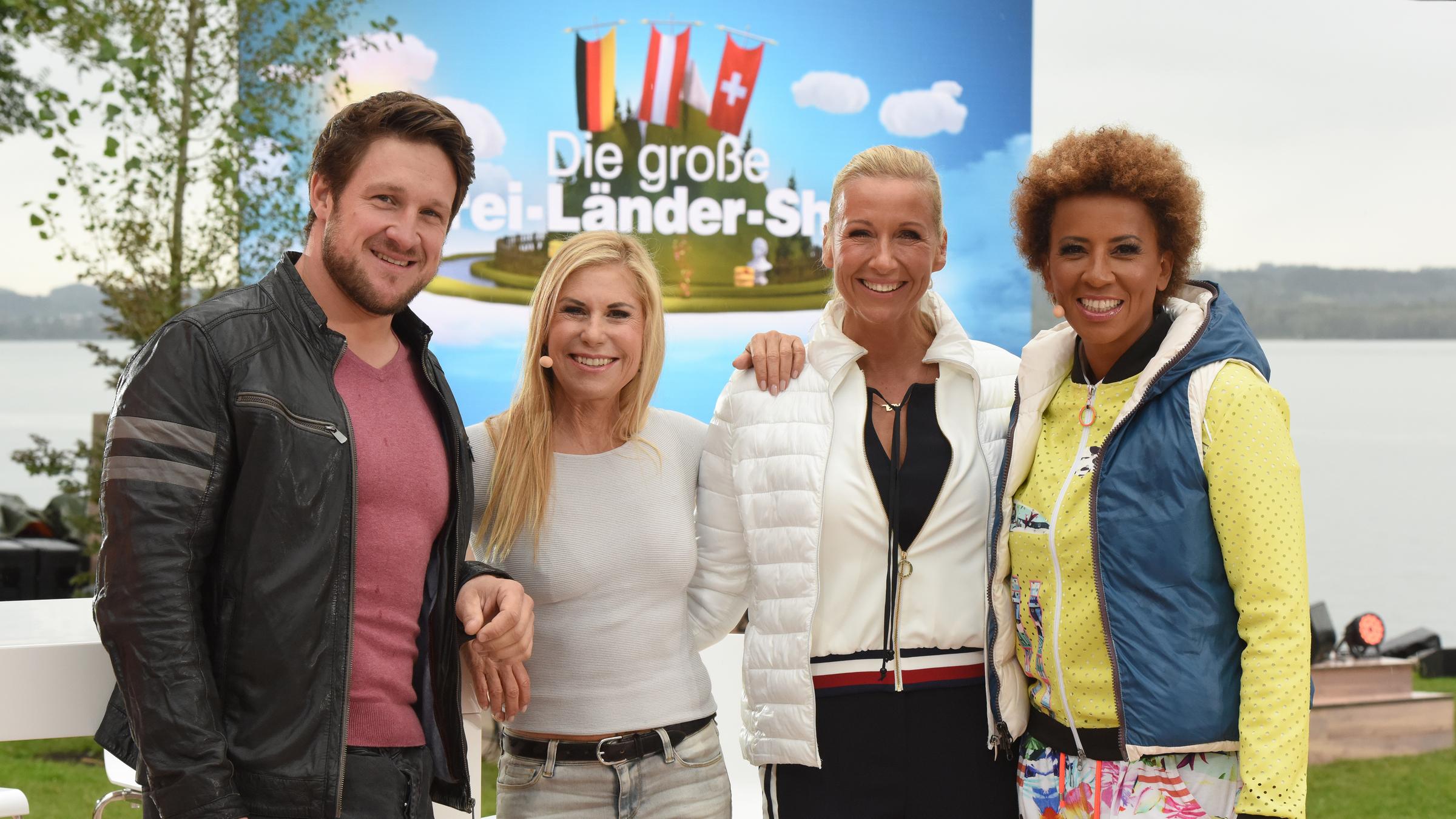 "Die Große Drei-Länder-Show": Matthias Steiner, Denise Biellmann, Andrea Kiewel und Arabella Kiesbauer am Ufer des Bodensees mit Kulisse im Hintergrund.