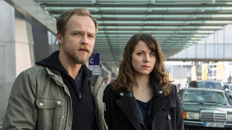 "Kommissar Marthaler- Die Sterntaler-Verschwörung": Kommissar Marthaler (Matthias Koeberlin) und seine neue Kollegin Sarah (Alice Dwyer) stehen vor der Ankunftshalle des Frankfurter Flughafens.