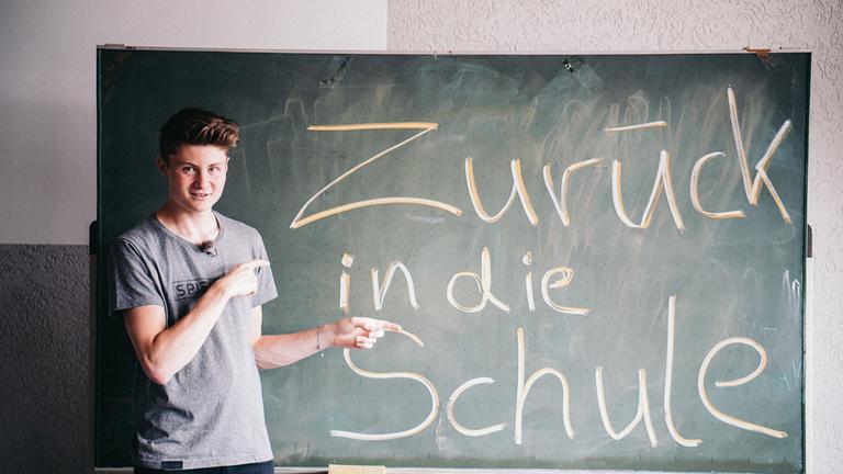 "#felixfragt - YouTube-Star auf Deutschlandcheck": YouTuber Felix von der Laden steht in einem Klassenraum vor einer Tafel, auf der geschrieben steht "Zurück in die Schule".