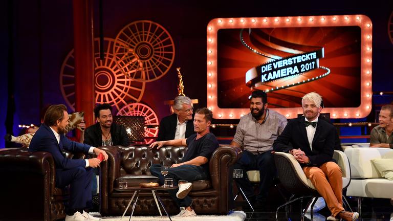 "Die versteckte Kamera 2017": Steven Gätjen, Til Schweiger, Andreas Ehrlich, Sky du Mont, Faisal Kawusi, Ross Antony und Fabian Hambüchen sitzen in großer Runde zusammen und unterhalten sich amüsiert.