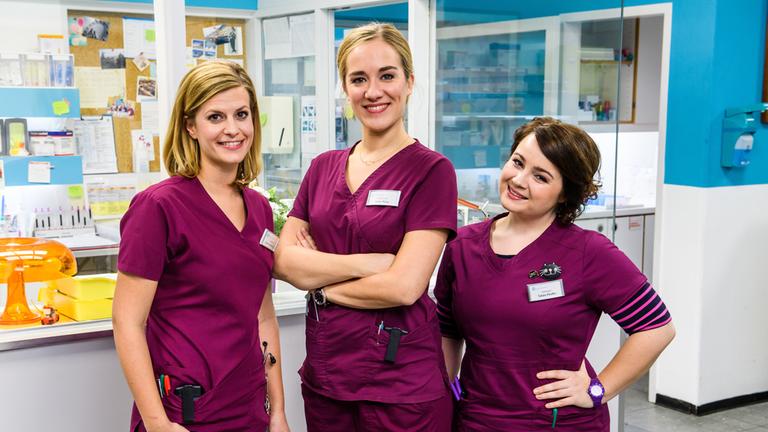 "Bettys Diagnose / Drehstart": Krankenschwester Betty Weiß (Annina Hellenthal, m.) mit ihren neuen Kolleginnen Lizzy (Theresa Underberg, l.) und Talula (Carolin Walter, r.) stehen gemeinsam auf dem Flur der Aufnahmestation.