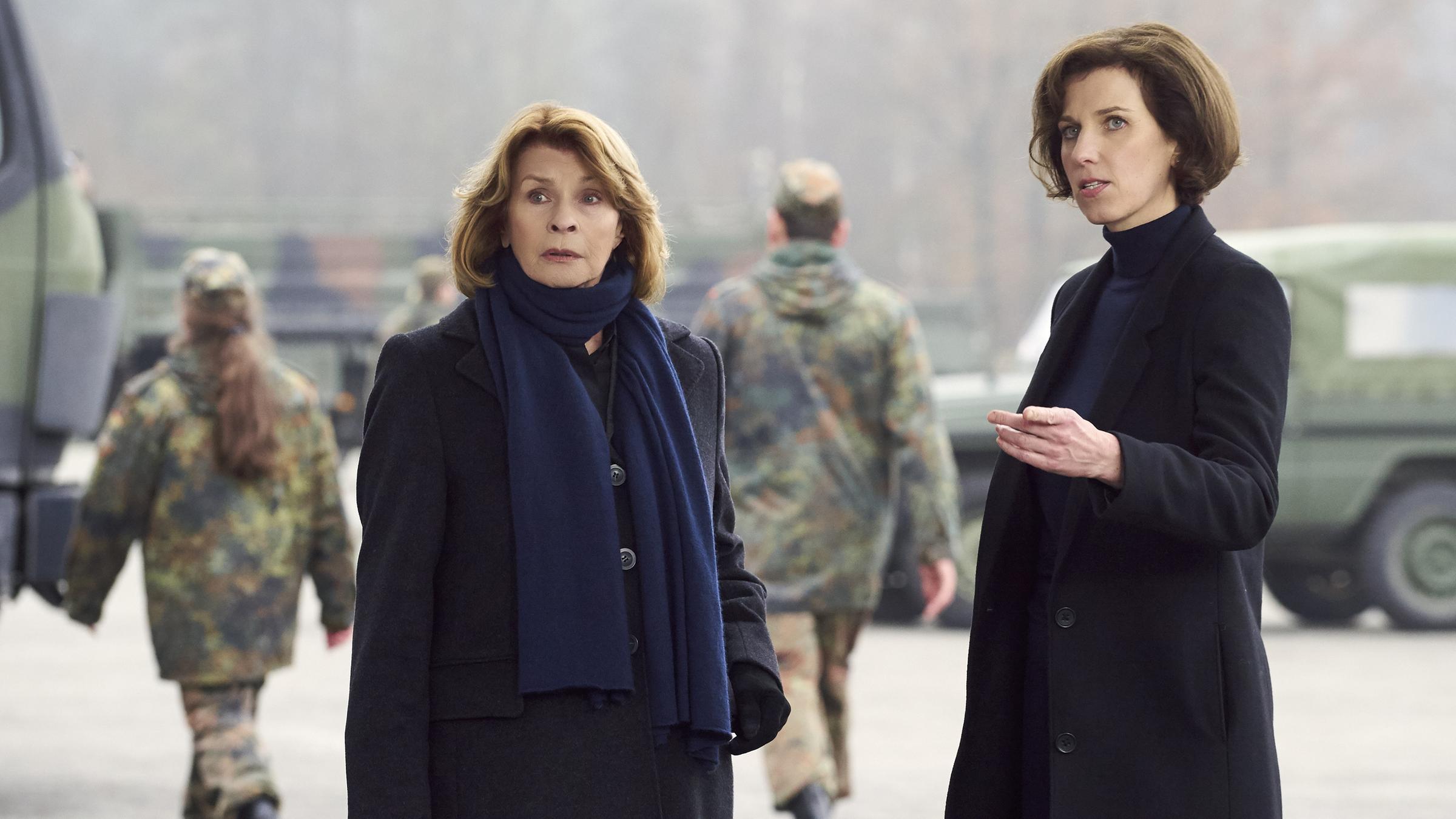 "Unter Verdacht - Verschlusssache": Dr. Eva Maria Prohacek (Senta Berger) und Sibylle von Eick (Hanna Scheibe) stehen auf dem Hof einer Bundeswehrkaserne und beobachten jemanden außerhalb des Bildes. Im Hintergrund sind Soldaten und Bundeswehrfahrzeuge zu erkennen.