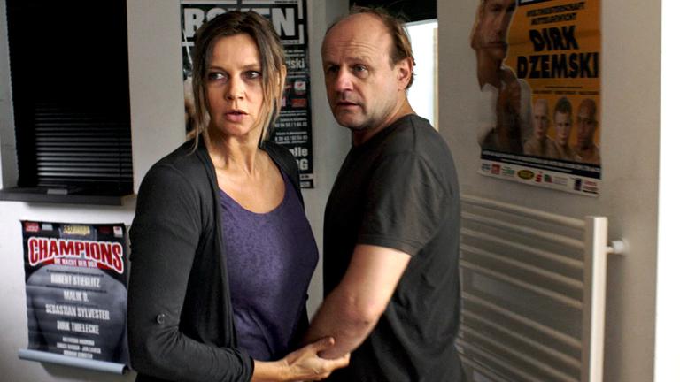 "Tod auf Raten": Annett Gräber (Veronica Ferres) und ihr Mann Ronald (Oliver Stokowski) stehen in einem Raum. Annett hält Ronald am Arm fest und schaut sich wütend um. Ronald sieht eher überrascht aus.