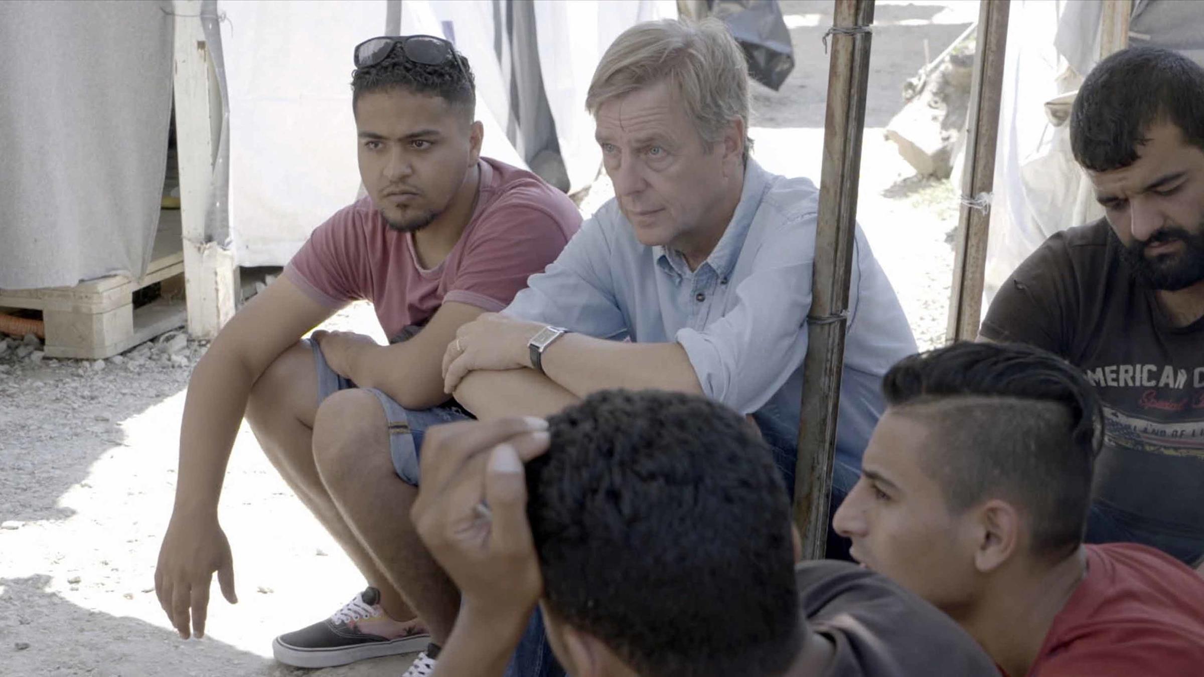 "UNANTASTBAR - Der Kampf für Menschenrechte": Claus Kleber und sein Übersetzer Issmail sitzen mit mehreren jungen Männern zusammen und schauen in die gleiche Richtung.