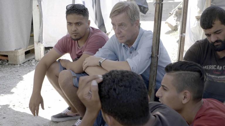 "UNANTASTBAR - Der Kampf für Menschenrechte": Claus Kleber und sein Übersetzer Issmail sitzen mit mehreren jungen Männern zusammen und schauen in die gleiche Richtung.