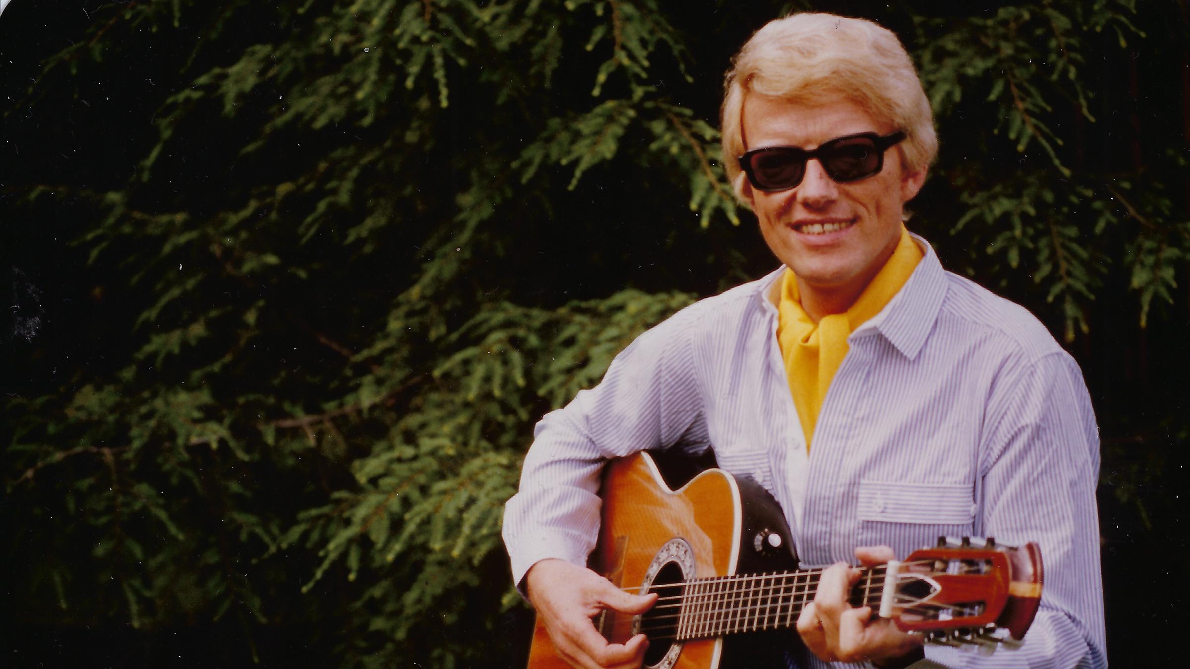 "ZDFzeit: Mensch Heino! Der Sänger und die Deutschen":  Heino mit Gitarre und Brille. Er trägt ein gelbes Halstuch.