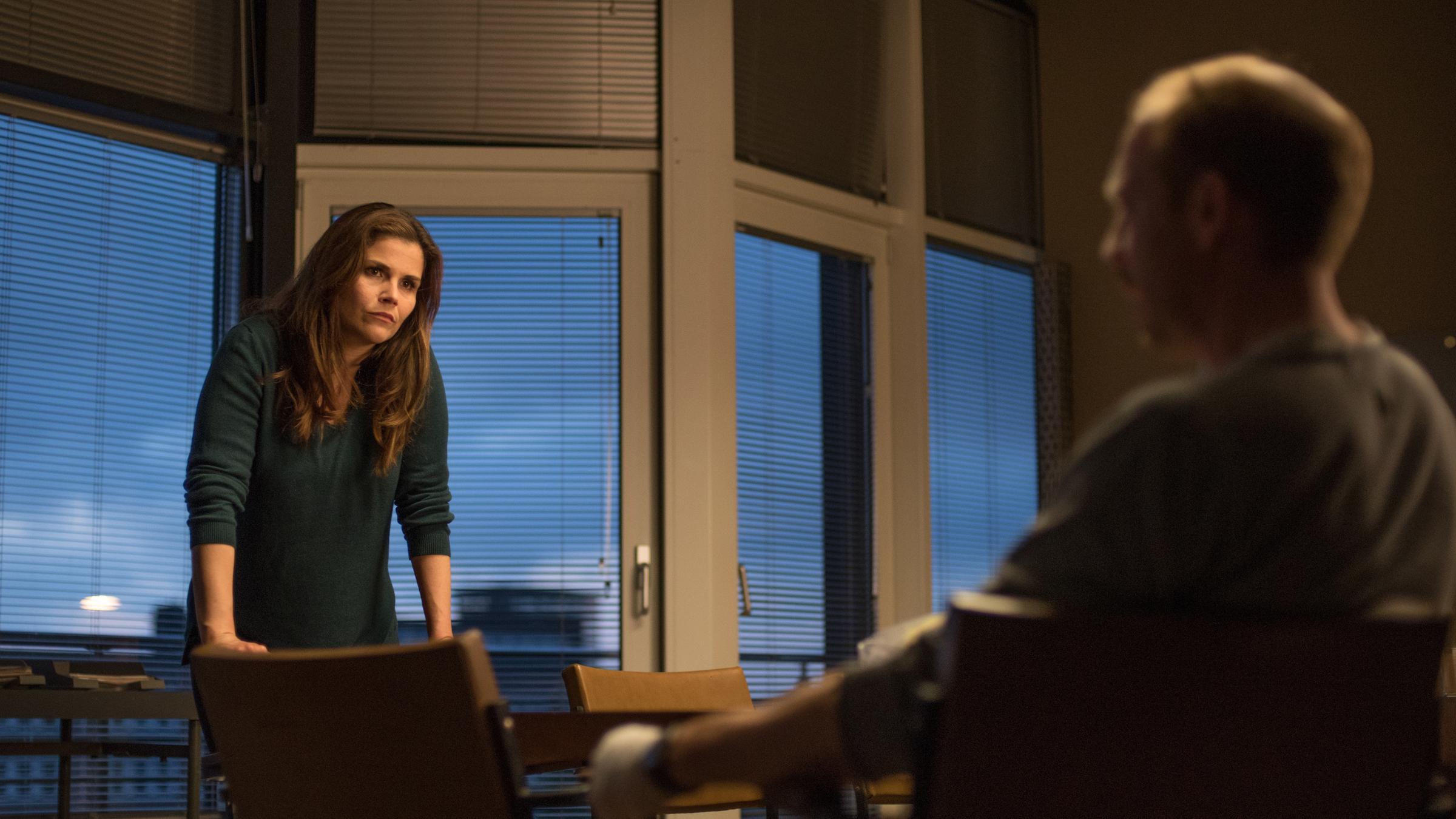 "Stralsund - Das Phantom": Nina Petersen (Katharina Wackernagel) steht in einem Büro vor Prof. Lauder (Johann von Bülow), der an einem Tisch sitzt, und schaut ihn eindringlich an.