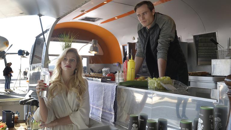  "Ein starkes Team – Preis der Schönheit": Leonie Seiters (Amelie Otto) steht mit einer Wasserflasche vor Patrick Heise (Christopher Reinhardt) in dessen Cateringwagen. Sie schaut ins Leere, während Patrick sie beobachtet.