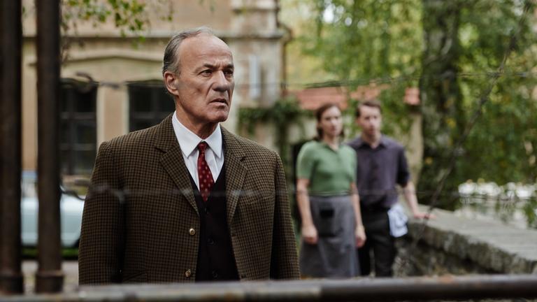 "TANNBACH - Schicksal eines Dorfes; Frieden aus Stein": Georg von Striesow (Heiner Lauterbach) steht auf der kleinen Steinbrücke, die ehemals Tannbach verbunden hat, und blickt Fassungslos auf den Stacheldraht-Zaun vor sich.