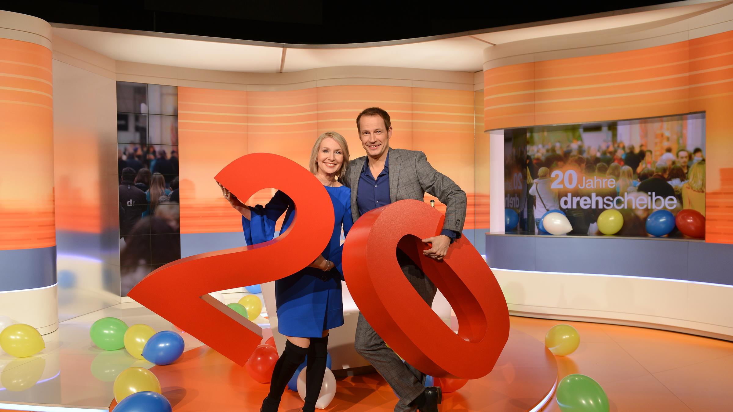 "drehscheibe": Babette von Kienlin und Tim Nidernolte in der Studiokulisse. Zum Jubiläum ist die Zahl 20 in großen, roten Ziffern in die Studiokulisse integriert.
