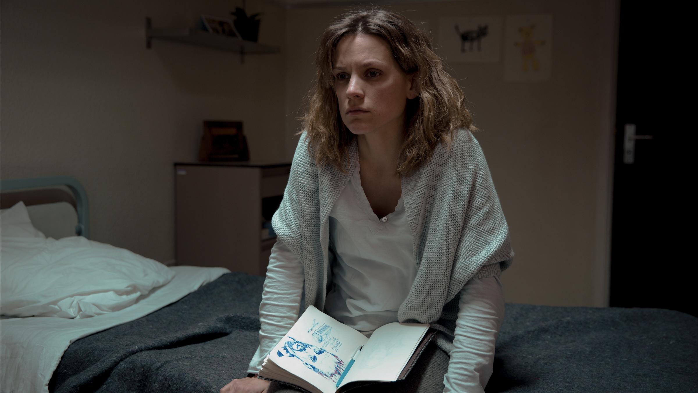 "Tabula Rasa - Der Sandsturm": Annemie D'Haeze (Veerle Baetens), genannt Mie, sitzt mit ihrem Notizbuch auf ihrem Bett in der Anstalt für psychisch Kranke.