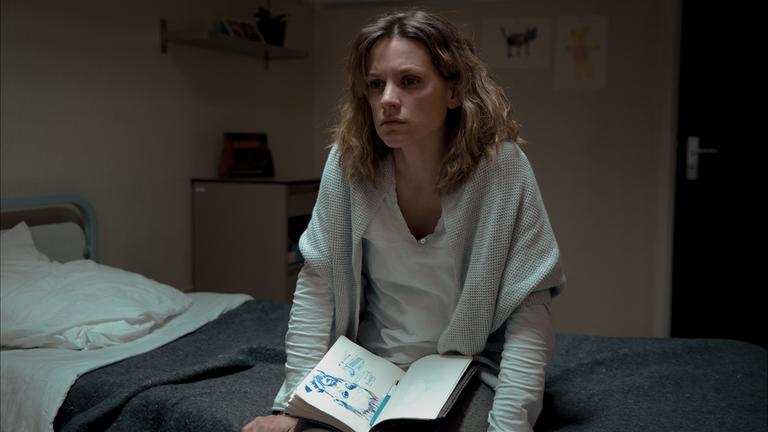 "Tabula Rasa - Der Sandsturm": Annemie D'Haeze (Veerle Baetens), genannt Mie, sitzt mit ihrem Notizbuch auf ihrem Bett in der Anstalt für psychisch Kranke.