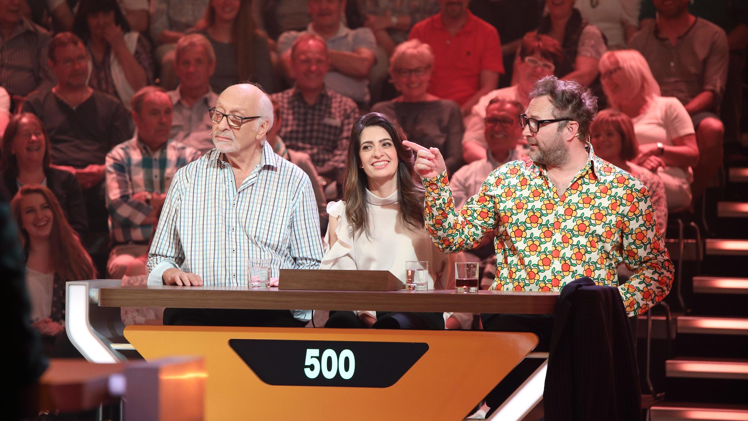 "Da kommst du nie drauf!": Von links nach rechts sitzen Karl Dall, Linda Zervakis und Paul Panzer an ihrem Pult im Studio. Die Punktzahl auf dem Pult zeigt "500". Im Hintergrund Publikum.