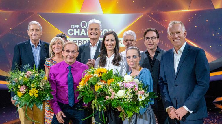"Der Quiz-Champion - Das Promi-Special": Ulrich Wickert, Ulrike von der Groeben, Tim Mälzer, Wigald Boning, Prof. Guido Knopp, Pinar Atalay, Marcel Reif, Anna Thalbach, Michael Bully Herbig und Johannes B. Kerner stehen im Studio und lachen in die Kamera. Die drei Frauen halten Blumensträuße in ihren Händen.