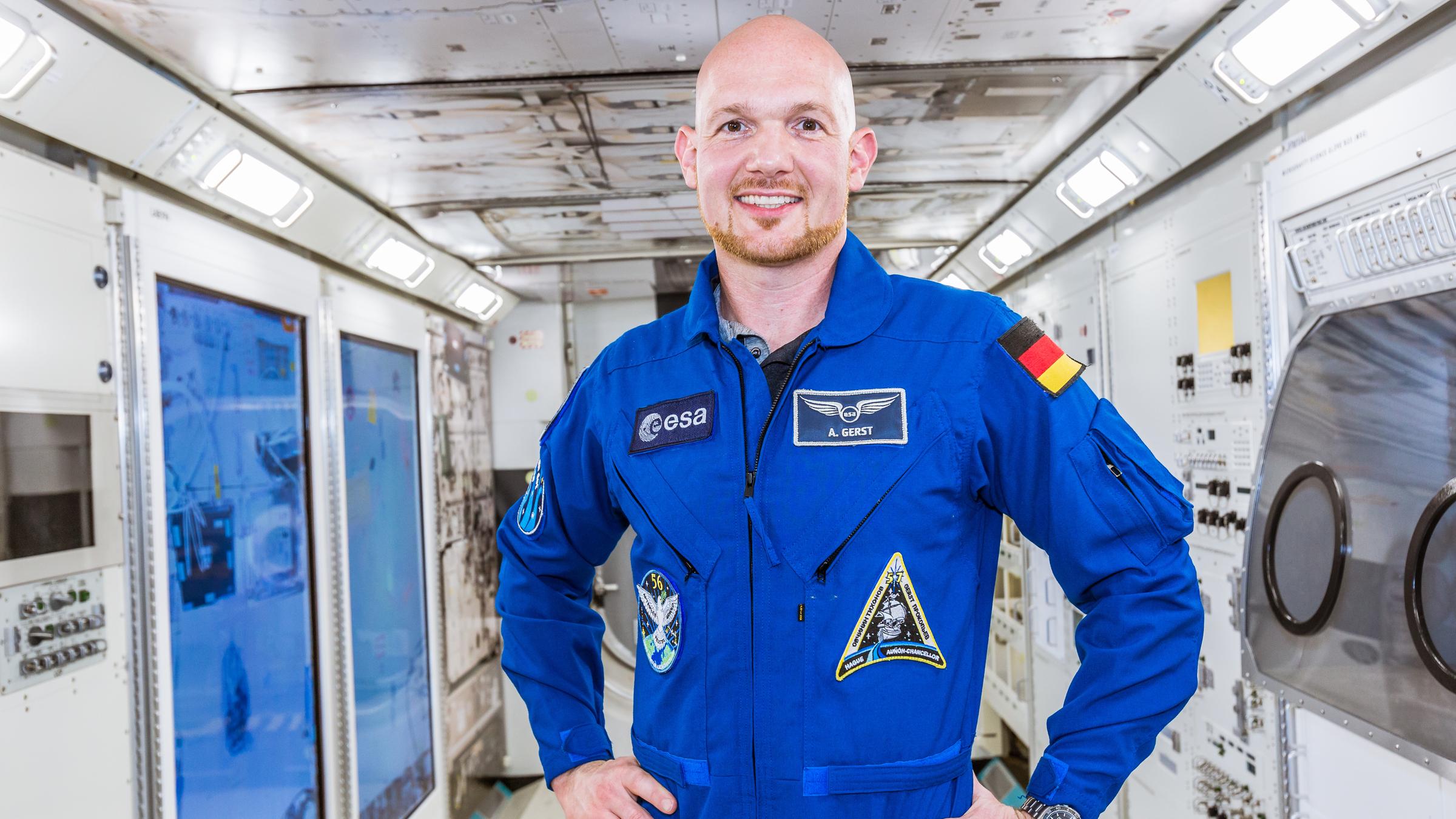 "Terra X: Aufbruch ins All - mit Alexander Gerst": Alexander Gerst im blauen Overall mit entschlossener Körperhaltung. Steht mittig in der Internationalen Raumstation ISS.