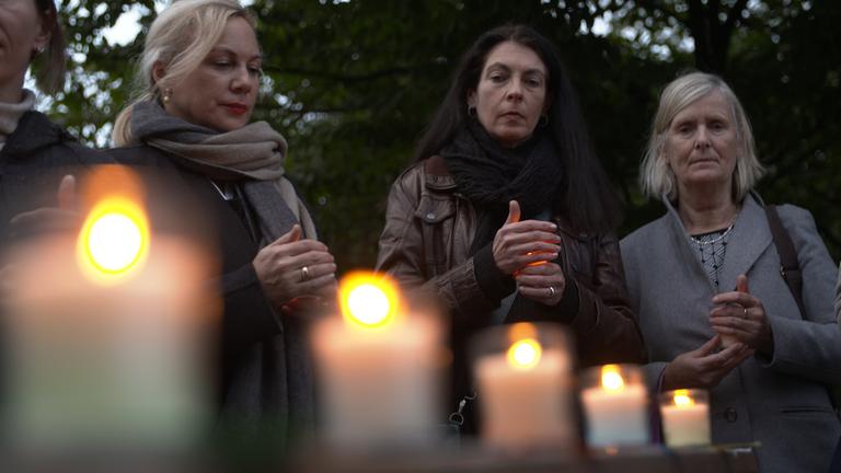"37°: Was bin ich ohne dich? - Wie Angehörige den Suizid überleben": Miriam und ihre Freundinnen halten kleine brennende Kerzen in der Hand. Sie stehen eng beieinander. Vor ihnen brennen weitere fünf Kerzen.
