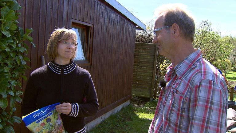  "planet e.: Gift im Garten": Heinz-Werner Hirschhäuser steht in einem Schrebergarten neben einer Frau, die eine Tüte Blaukorn hält.
