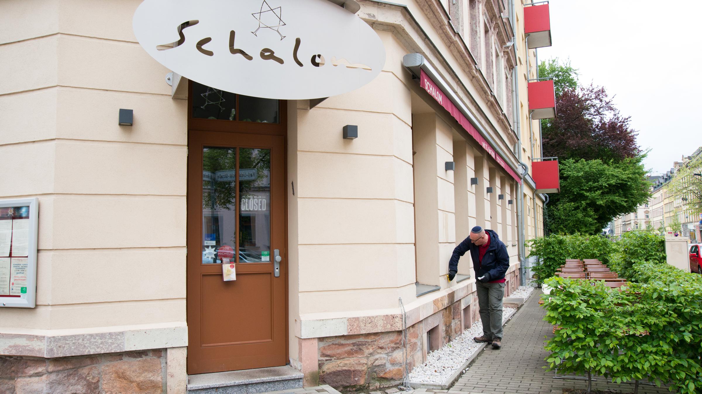 "ZDF.reportage: Alles koscher? Deutsche Juden verstehen ihr Land nicht mehr": Uwe Dziuballa reinigt die Hauswand seines Restaurants – das Schalom in Chemnitz.