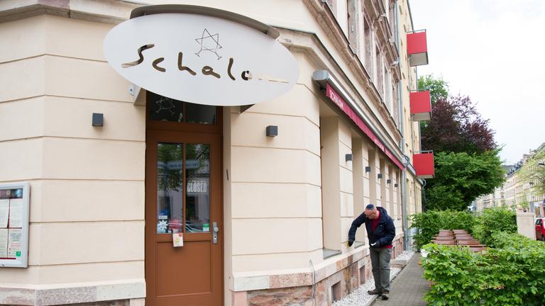 "ZDF.reportage: Alles koscher? Deutsche Juden verstehen ihr Land nicht mehr": Uwe Dziuballa reinigt die Hauswand seines Restaurants – das Schalom in Chemnitz.