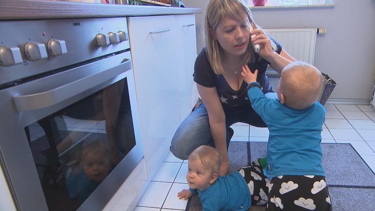 "37°: Erst die Kinder, dann ich - Alleinerziehende am Limit": Christiane hockt mit ihren Zwillingen am Boden in der Küche und hat ein Telefon am linken Ohr. Eins der Kinder versucht, nach dem Telefon zu greifen.