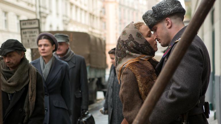"Kind 44": Leo (Tom Hardy) und Ehefrau Raisa (Noomi Rapace) stehen auf einer Straße dicht zusammen und sind kurz davor, sich zu küssen.